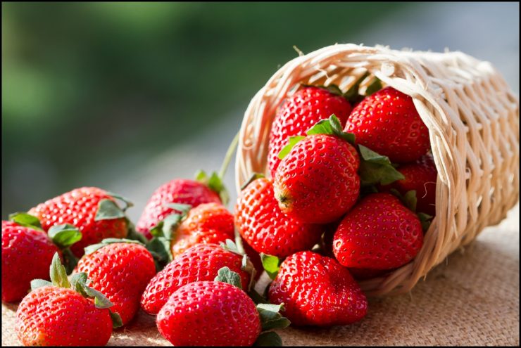 A small basket full of strawberries in natural background
