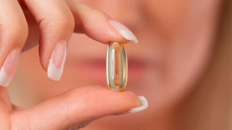 Close up of Caucasian woman with manicured fingernails holding capsule